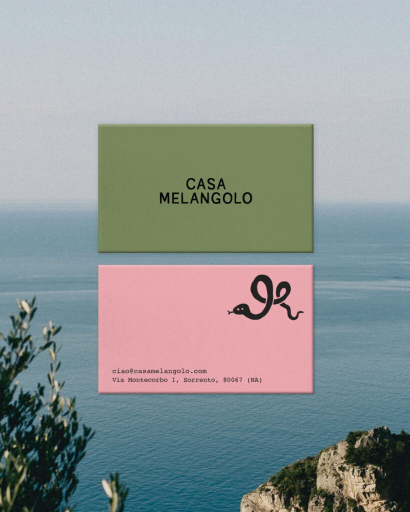 This image displays the design of Casa Melangolo's business cards. The front has the brand's black logo on a green background, whilst the back has the guesthouse's contacts on a pink background with the brand's snake symbol as a detail.