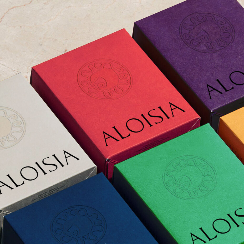 The photo show a set of boxes designed for the jewelry brand Aloisia, whose visual identity and art direction was curated by Osmo. The boxes have the brand's colours and display the logo and their symbol.