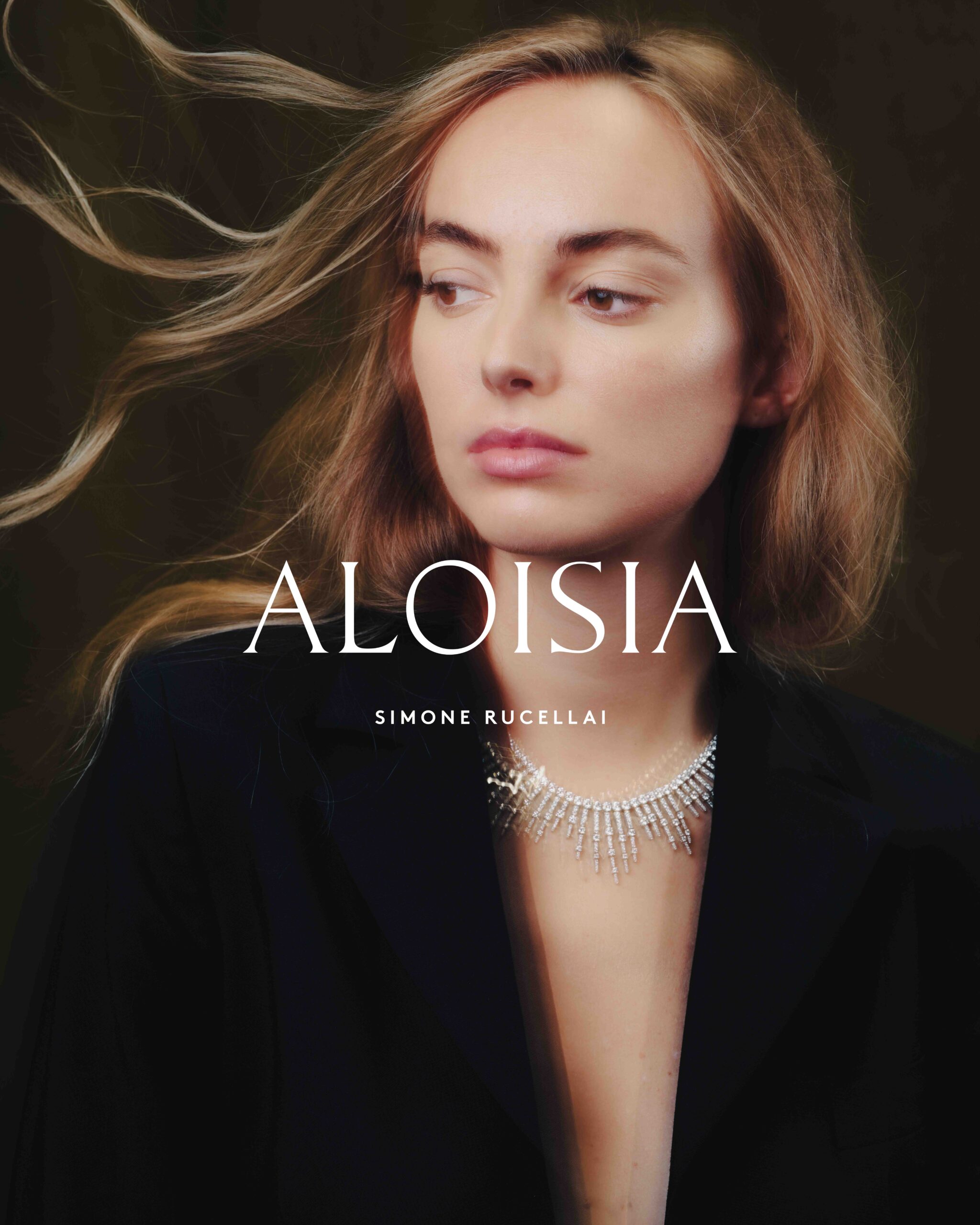 A photography of a model wearing a black suit and an elegant necklace for Aloisia, a jewelry branding. The photo displays the brand's logo made by Osmo.